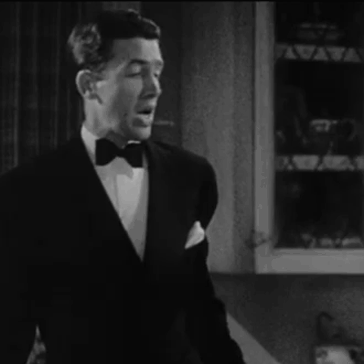James Stewart turns and speaks. He's wearing a dinner suit with a white pocket handkerchief in a kitchen - animated gif