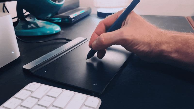 An animation showing a human hand using a graphics tablet with a pen, then switching to use a Magic Trackpad nearby, then switching back again.