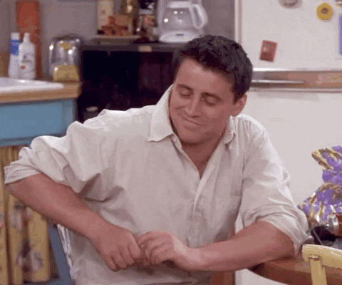 Friends gif. Matt LeBlanc as Joey seated in a chair, smiling softly as his eyes grow wide. His smile fades into a stern then surprised face as his mouth drops open, clearly shocked by what he's looking at off screen.