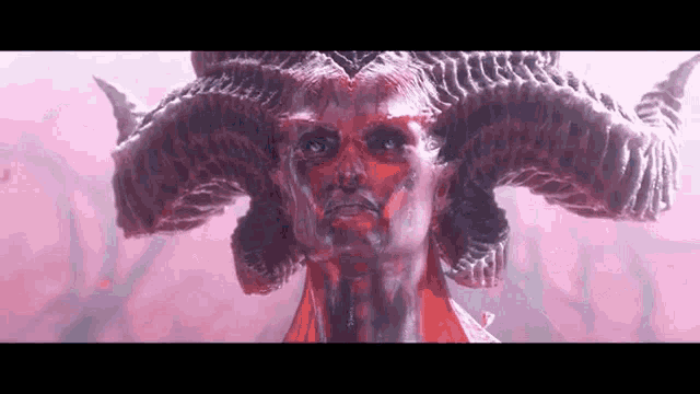 a close up of a statue of a demon with horns on his head .