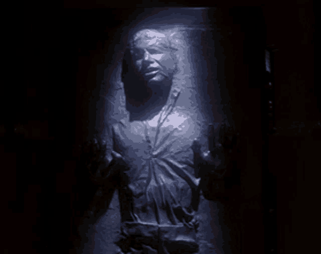 a statue of a man in a dark room with his hands outstretched