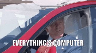 a man is driving a red car with the words " everything 's computer " on the bottom