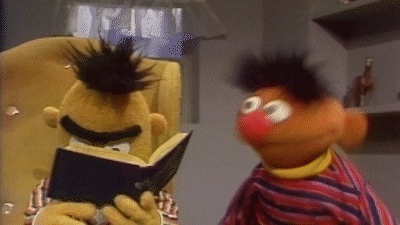 Sesame Street gif. Bert reads a book as Ernie, laughs energetically beside him. Bert's head slowly rises from the book as if in frustrated annoyance.