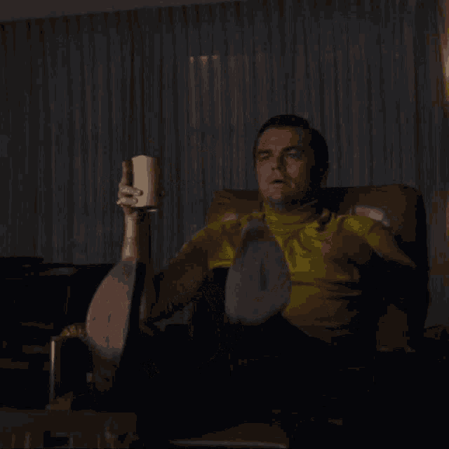 a man in a yellow shirt is sitting in a chair pointing at something