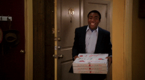 A GIF of Donald Glover opening a door with pizzas in hand, shocked to discover the room in flames and total chaos—a classic meme used to depict returning to a disaster.