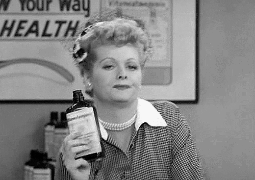 GIF of Lucille Ball clutching a bottle and drunkenly winking at the camera