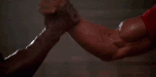 A Gif of two body builders gripping palms in an arm wrestling position: Depicting Partnership