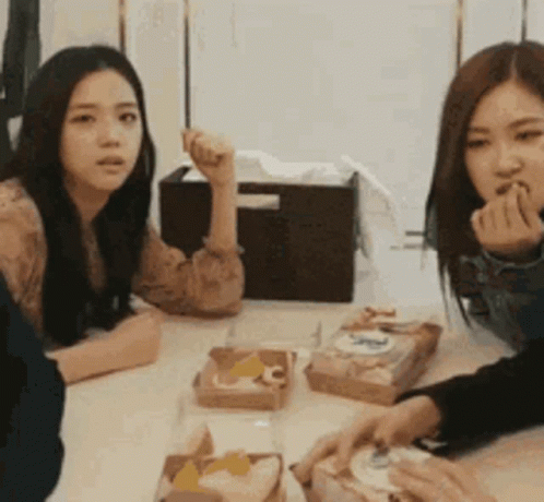 a group of women are sitting at a table with boxes of food including a box that says ' nc ' on it