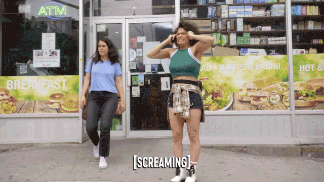 Gif of Ilana in Broad City screaming outside a bodega on a busy sidewalk