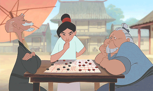Gif dal cartone animato "Mulan" con una ragazzina di origini asiatiche, vestiva con una tunica bianca e un fiocco rosso tra i capelli neri: afferra in mano una pedina da un gioca da tavolo e lascia esterrefatti due uomini anziani, vestiti con kimono verde e azzurro, entrambi seduti di profilo al tavolo. Sullo sfondo delle pagode, terreno giallo e a sinistra un grosso ombrellone arancio-rosa che fa ombra ai tre personaggi.
