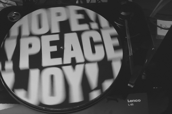 A turntable with a slipmat that reads Hope! Peace! Joy!
