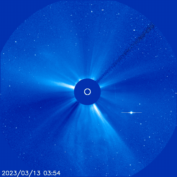 In this image from a NASA spacecraft, the Sun's solar wind streams out from a central point in the image (covered to block the Sun's bright light). Suddenly a blast of gaseous looking white material is ejected from all around the blocked portion. A bright light point -- Mercury -- is visible off to the lower right