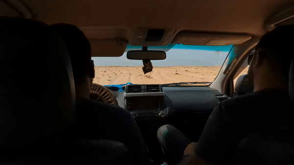 GIF of two people bouncing in the front seats of a 4x4 car driving through the desert