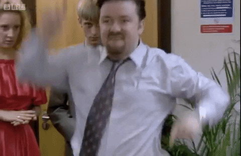  Gif of Ricky Gervais as David Brent in the Office performing an embarrassing dance in front of a crowd of people in an office