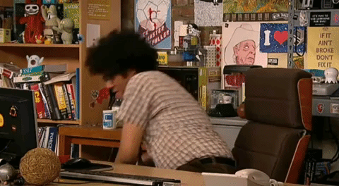 TV gif. Richard Ayoade, as Moss from The IT Crowd, cheerfully pulls a soda and a bucket of popcorn from under his desk. Text: "Ok ok..." He then turns to right of frame, eager to listen as he starts eating the popcorn. Text: "Go!"
