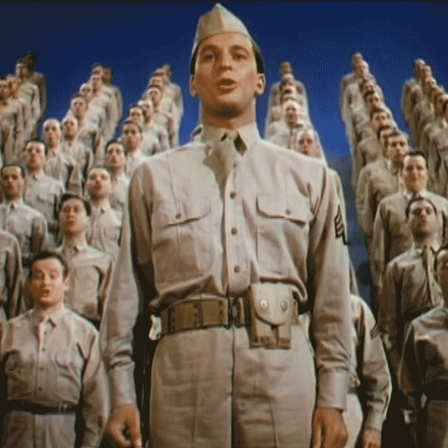 A soldier sings out on stage during 1943 film This is the Army. Behind him dozens of other soldiers, arranged on a staircase, sing too - animated gif
