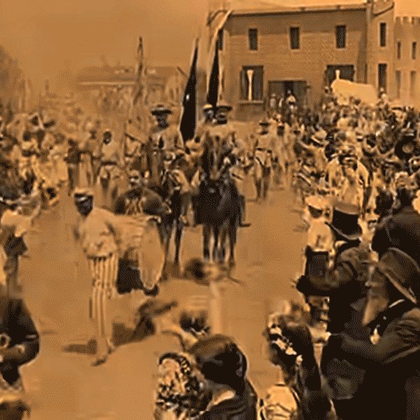 Animated gif showing a parade scene from the 1914 film The Birth of a Nation - confederate soldiers on horses parade through a town, a crowd waves and cheers