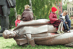 Children sit on a statue of Stalin, in the Fallen Monument  park in Moscow