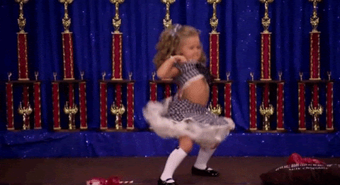 TV gif. A dressed-up little girl on Toddlers and Tiaras dances in a twerking motion, pumping her fists forward.