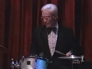 an older man in a tuxedo playing drums