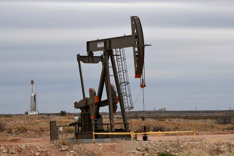 A pump jack operates in front of a drilling rig owned by Exxon near Carlsbad, New Mexico on February 11, 2019 [File: Reuers/Nick Oxford]