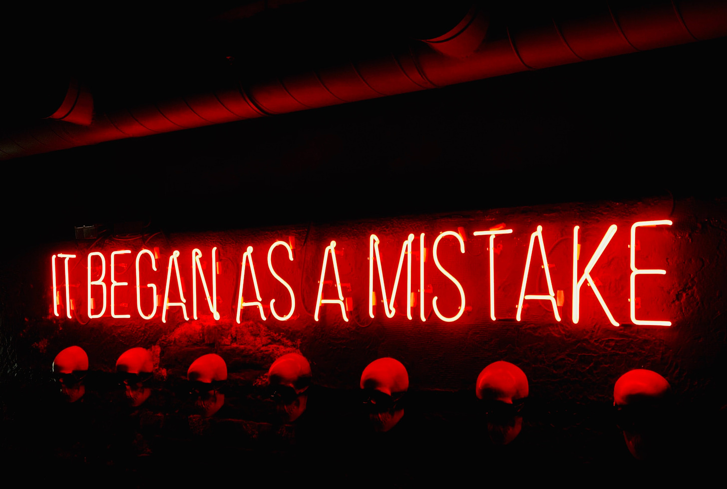 Neon sign that reads It began as a mistake.