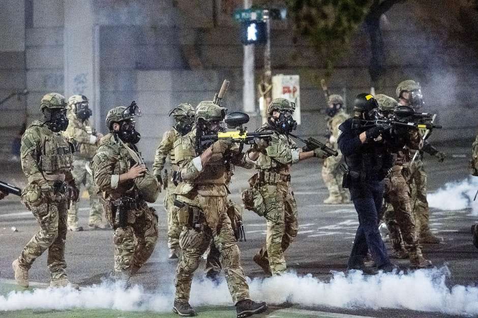 Federal agents use crowd control munitions to disperse Black Lives Matter protesters at the Mark O. Hatfield United States Courthouse on Monday, July 20, 2020, in Portland, Ore. Officers used teargas and projectiles to move the crowd after some protesters tore down a fence fronting the courthouse. (AP Photo/Noah Berger)