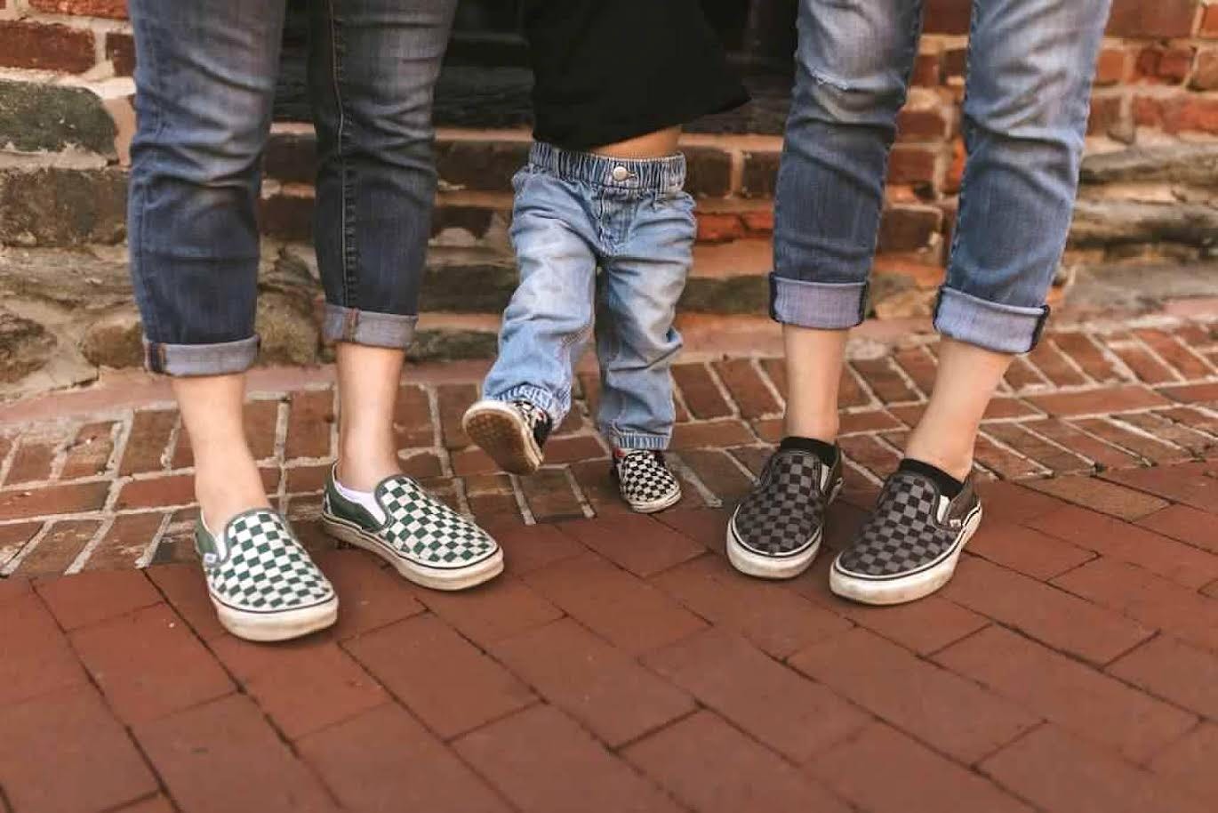 Three pairs of checkered vans shoes on brown brick. 