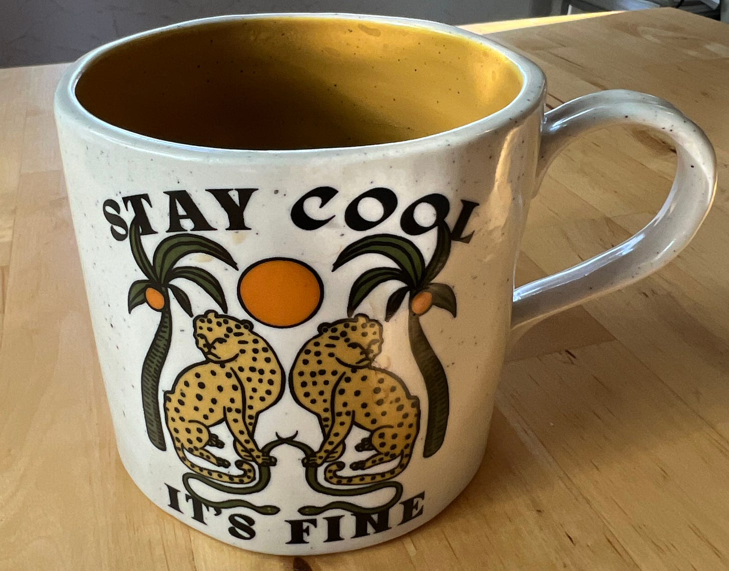 A mug on a table with two leopards on it that reads, Stay Cool, It's Fine