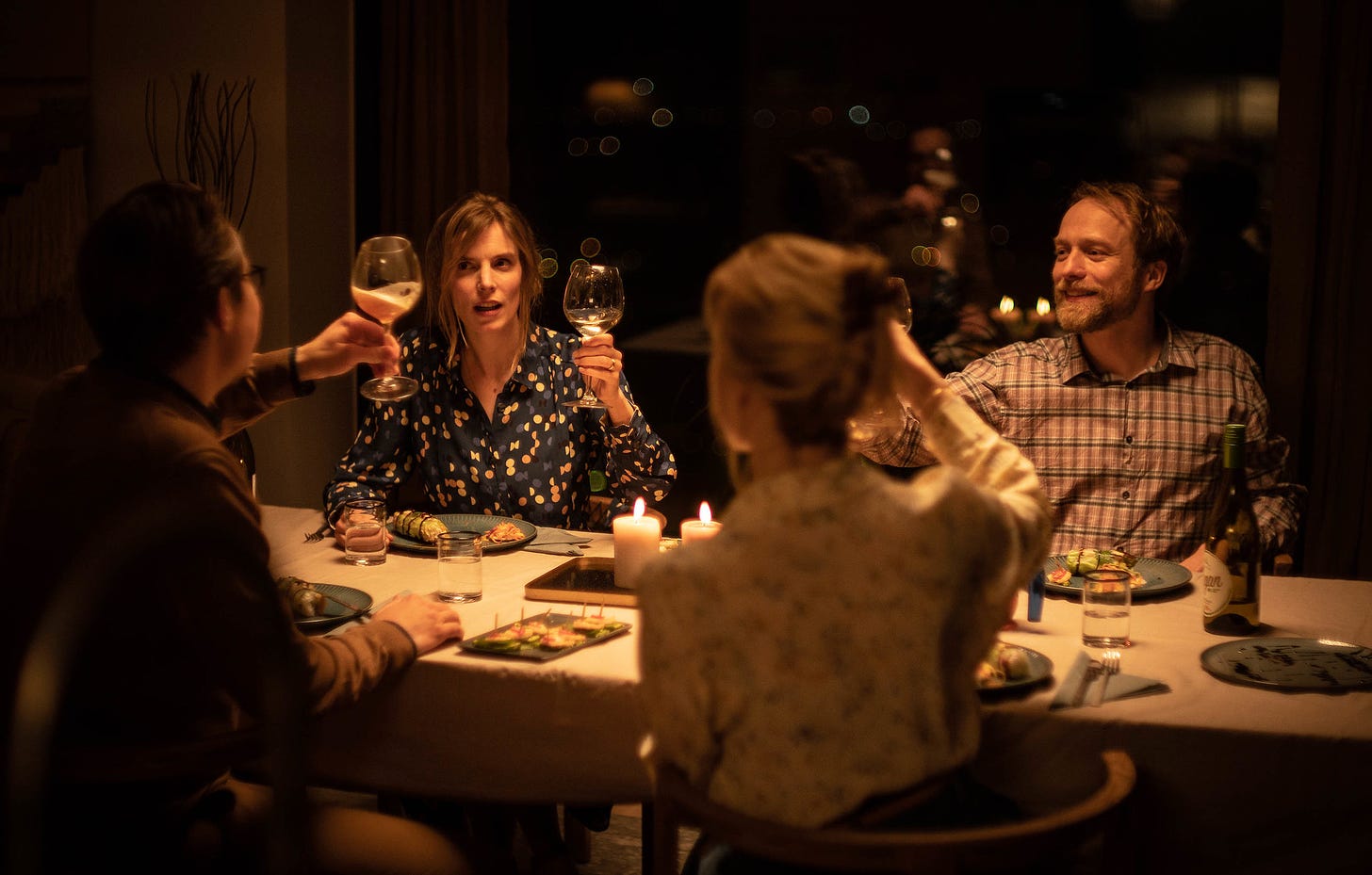 A group of four people at dinner raising their wine glasses in a toast, a still from Speak No Evil