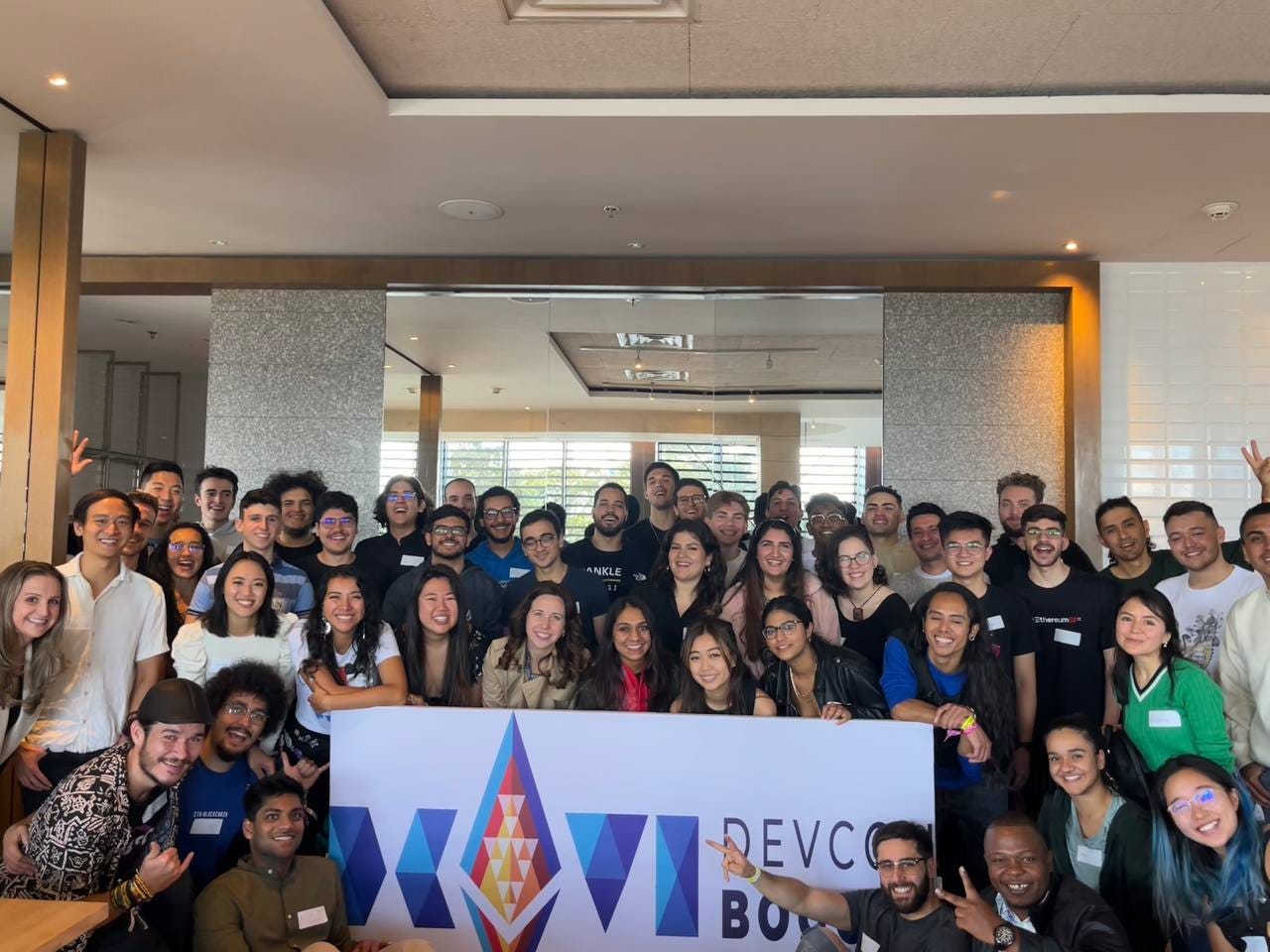photo of all the devcon scholars together in front of a devcon sign. this is from our devcon breakfast