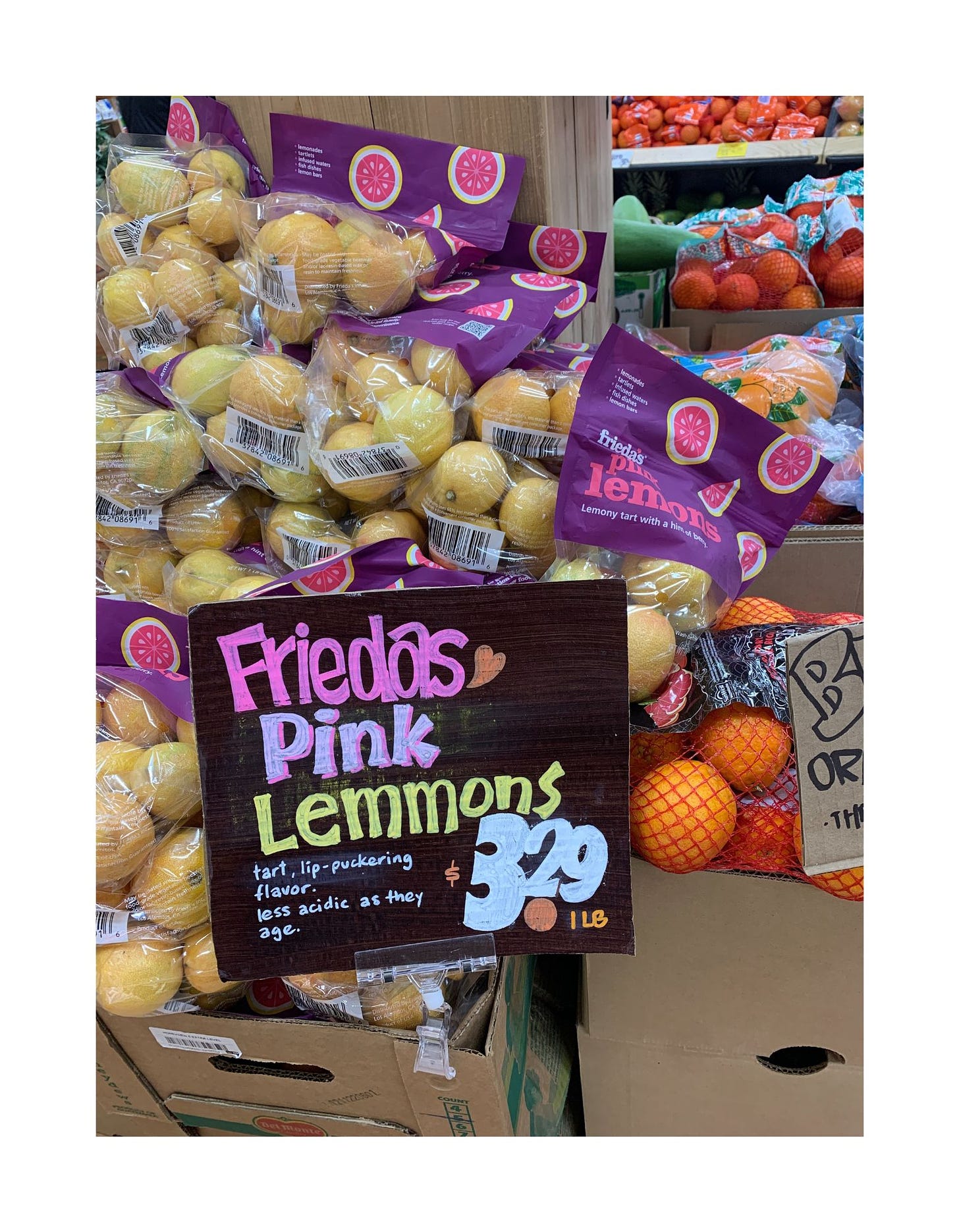 A grocery store display of lemons with a sign that says "Friedas Pink Lemmons"
