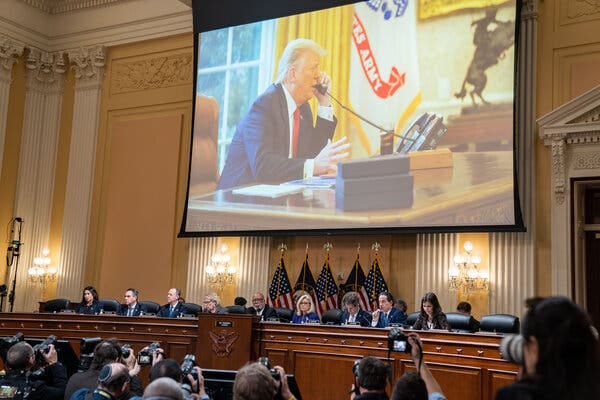 An image of former President Donald Trump appears on a screen above members of the House Jan. 6 panel during a hearing.