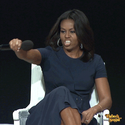Michelle Obama, seduta su una poltrona bianca, allunga la mano con cui stringe il microfono e dice "Drop the mic", poi ride.