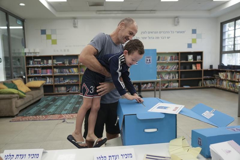 A man and his son vote during Israeli elections in Tel Aviv, Israel, Tuesday, Nov 1, 2022. (AP Photo/Oded Balilty)
