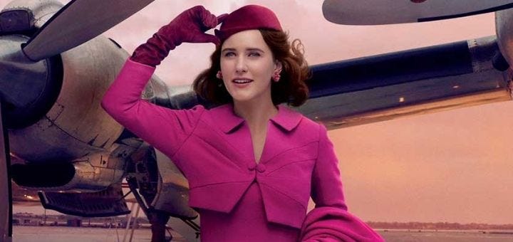 A woman wearing a dark pink suit, gloves, and hat, with a propeller plane in the background