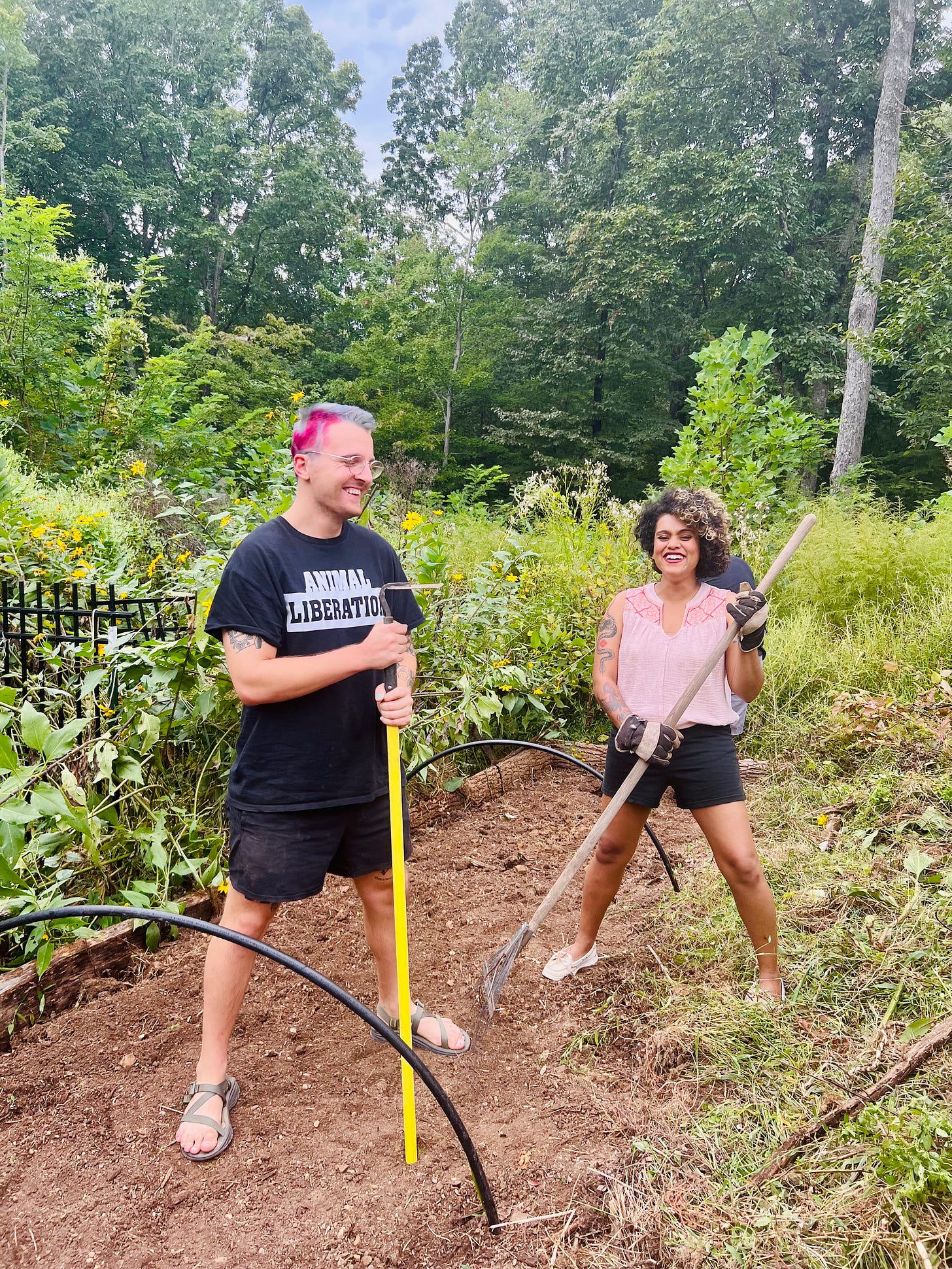 Ayesha and a friend plowing and prepping the garden soil bed to plant seeds in a sanctuary community farm on a mountain in Middle Tennessee.