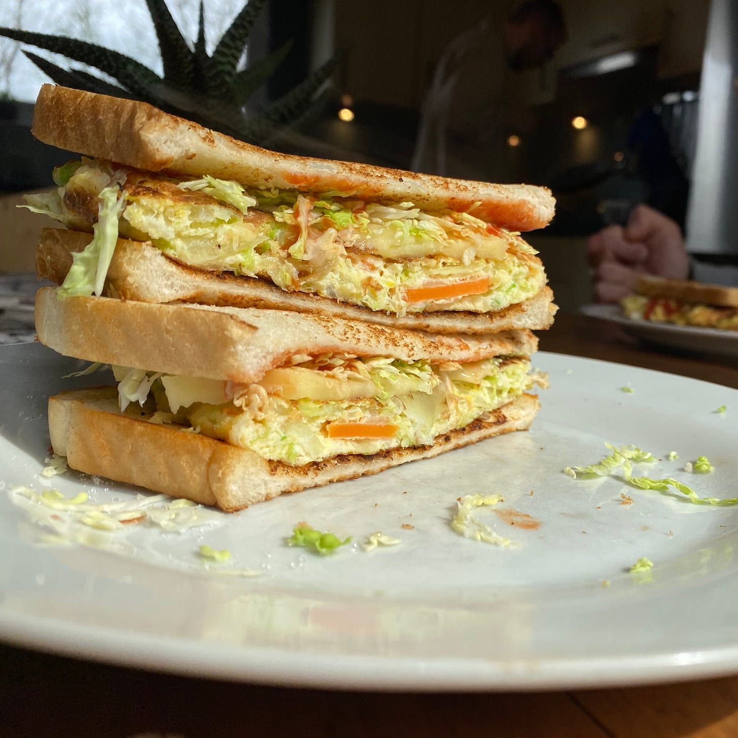 Image shows cut open toasted sandwich filled with shredded vegetable omelette