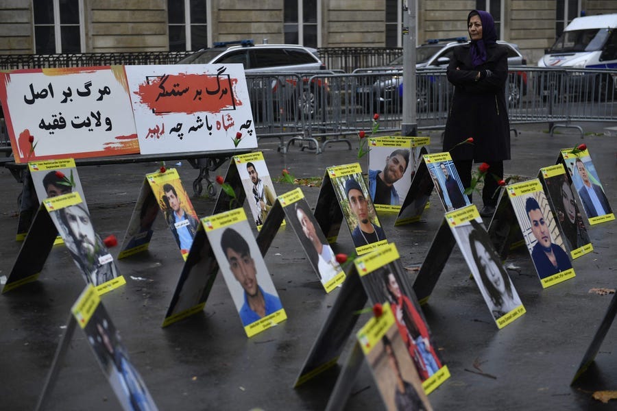 A protester stands next to placards with portraits of the victims of Iran's repression, near the French National Assembly in Paris on December 6, 2022.