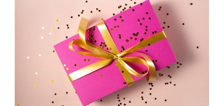 stock photo of a gift wrapped in hot pink paper with a gold ribbon