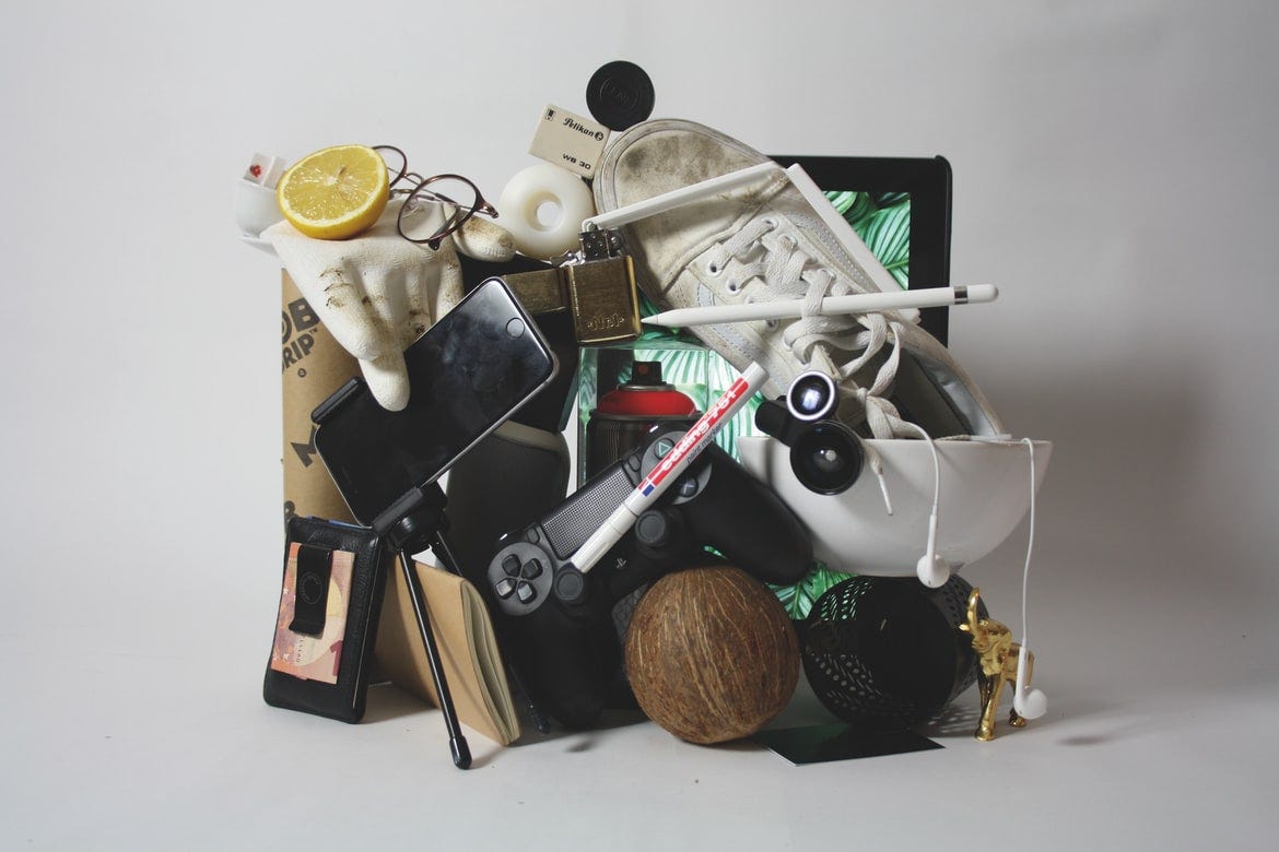 vários objetos empilhados, óculos, tênis, celular, objetos diversos, num emaranhado