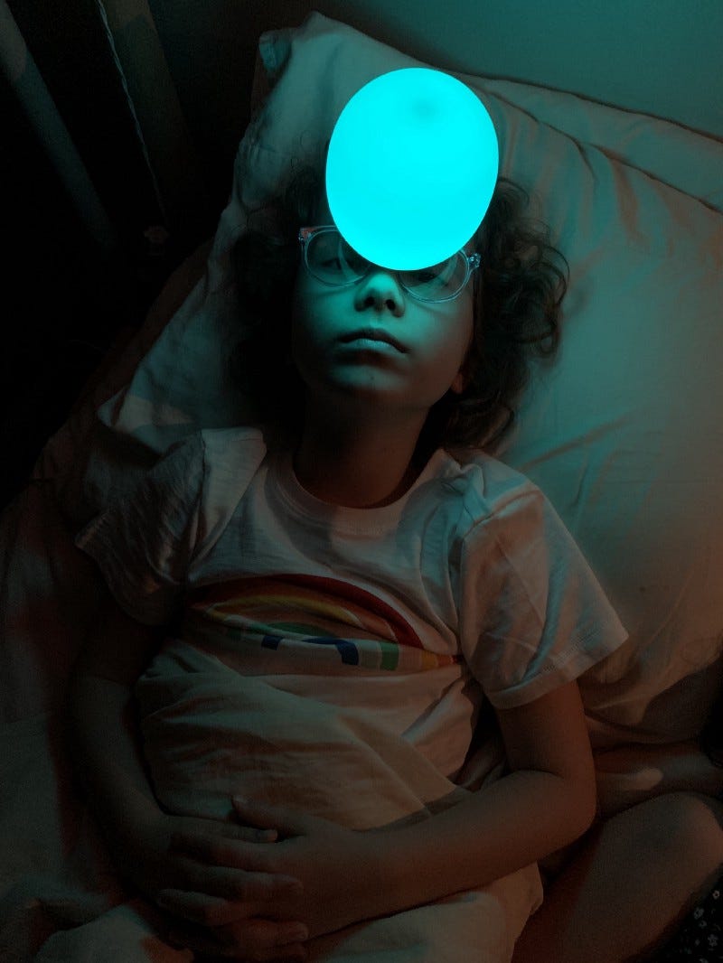 a seven year old kid balances a glowing blue light on her glasses