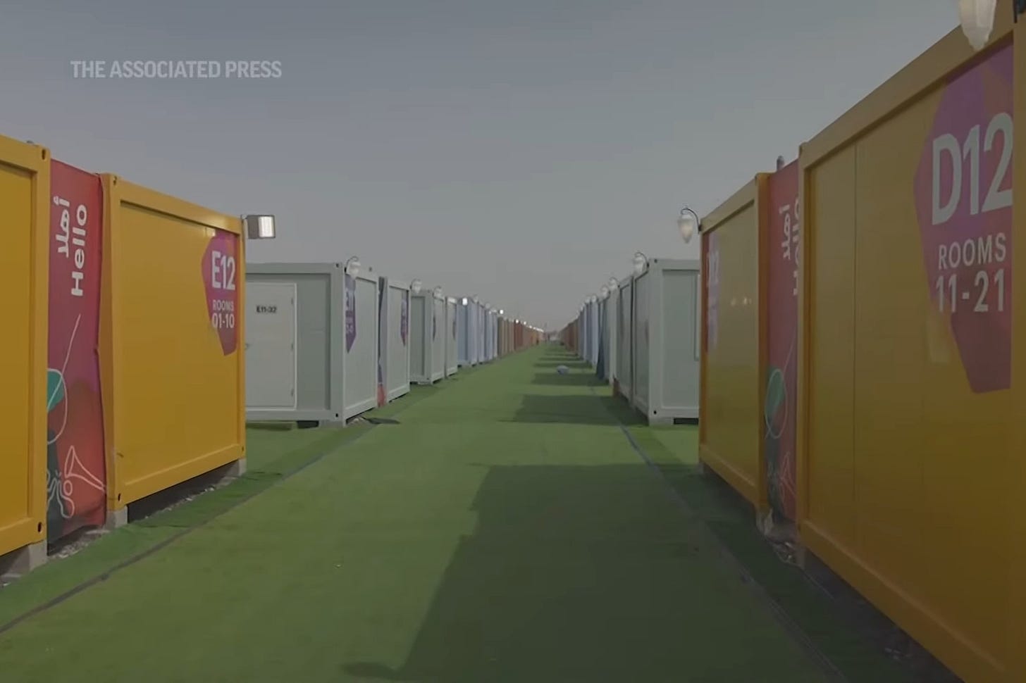 Image shows rows of shipping container cabins and artificial grass with a hazy desert sky in a video tour through the World Cup fan village in Qatar. Image shows rows of shipping container cabins and artificial grass with a hazy desert sky in a video tour through the World Cup fan village in Qatar.