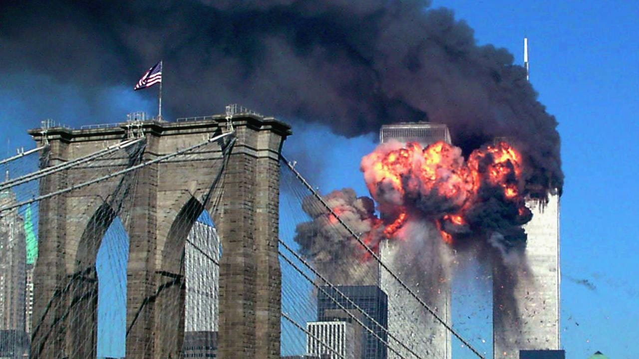 Image of the Twin Towers on fire with the Brooklyn Bridge in the foreground