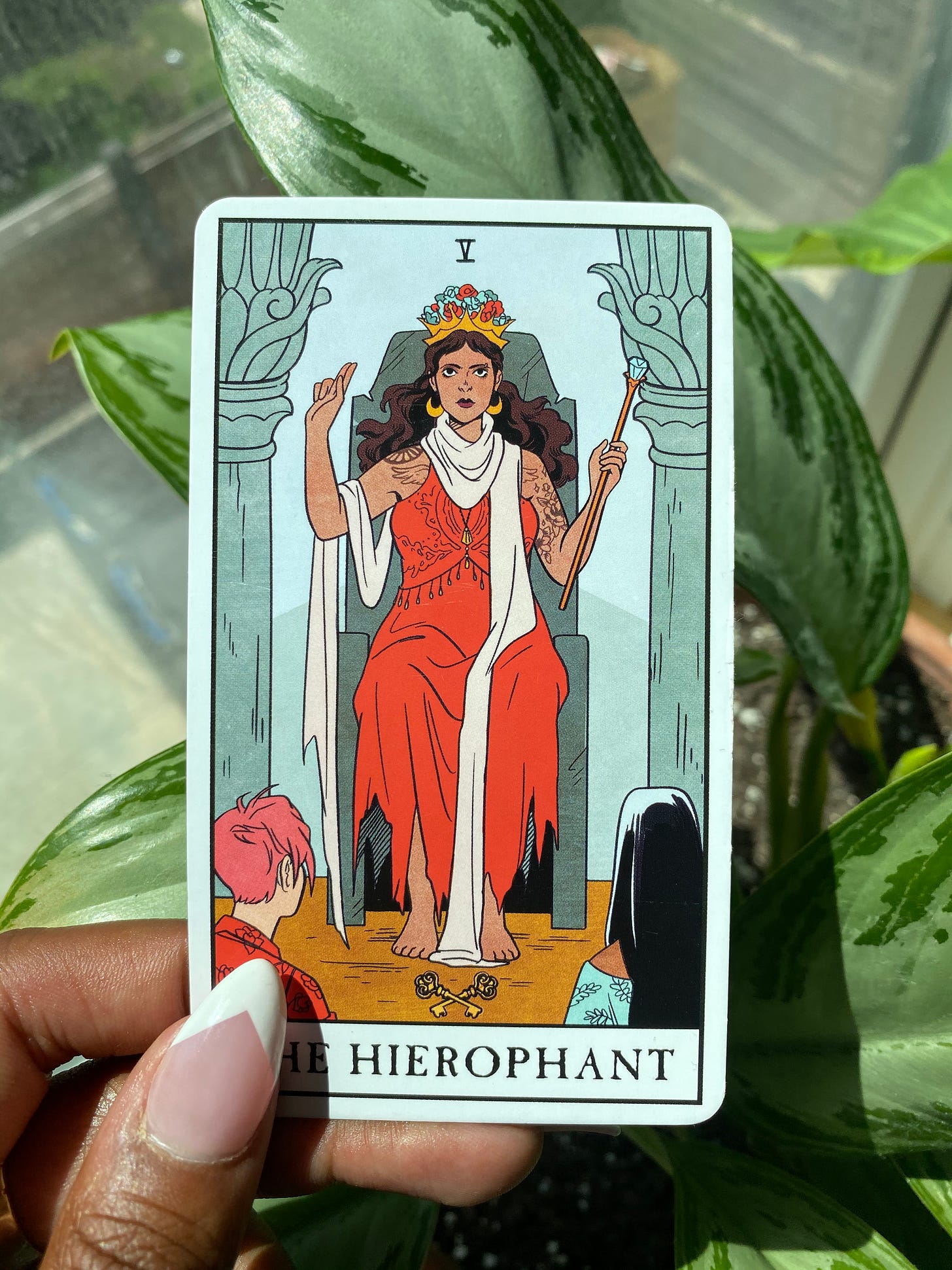 the hierophant tarot card with a woman wearing red dress with white shawl wrapped around her, two people look at her