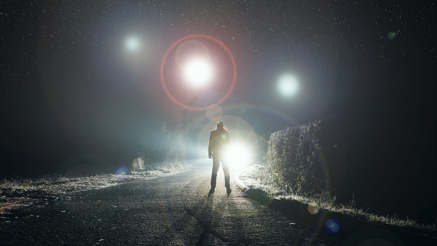 human figure on curving road with orbs hovering in the sky