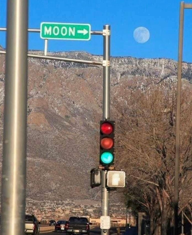 Traffic light and a sign pointing toward a moon with the word Moon written on the sign