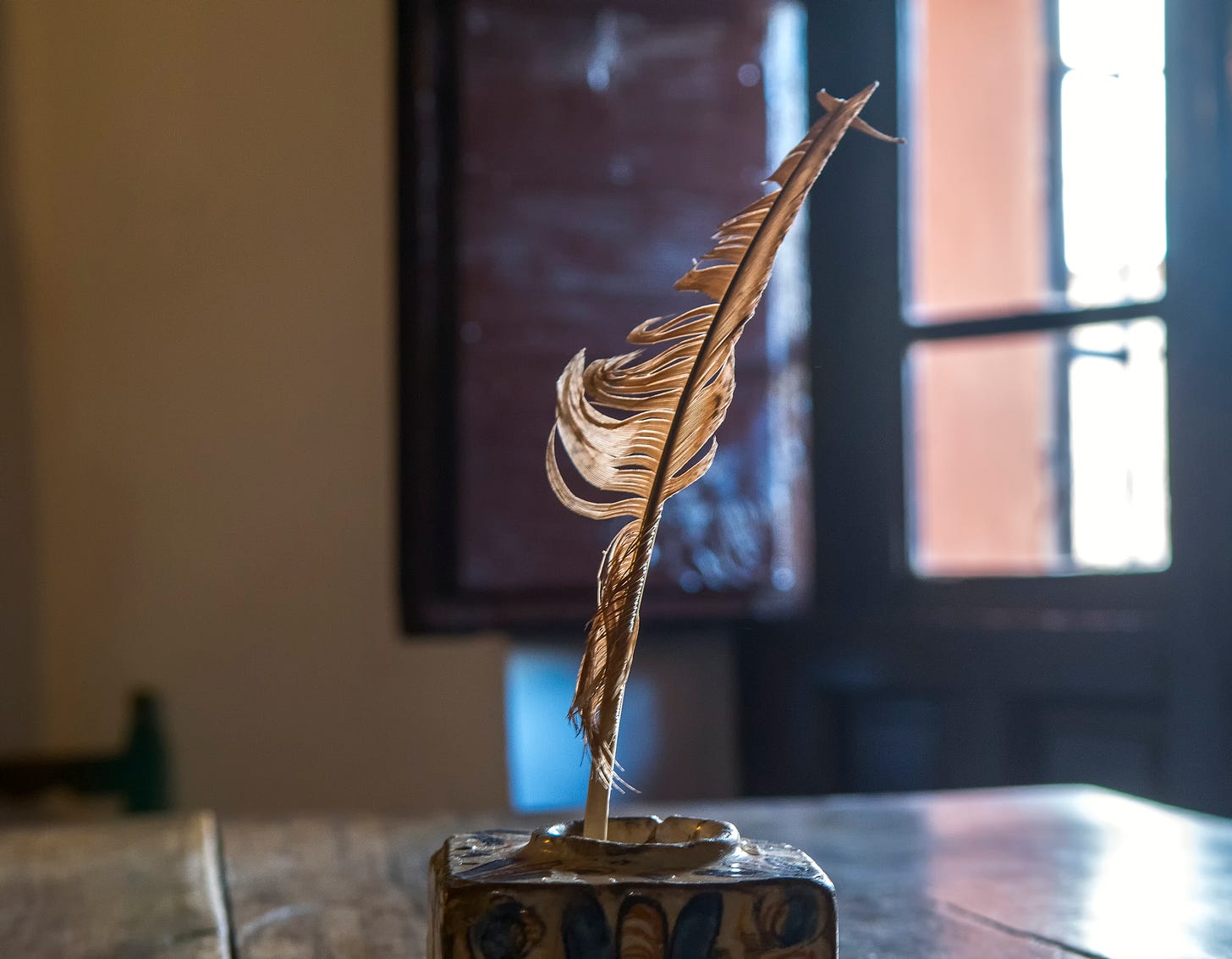 Quill pen in holder on table next to open window