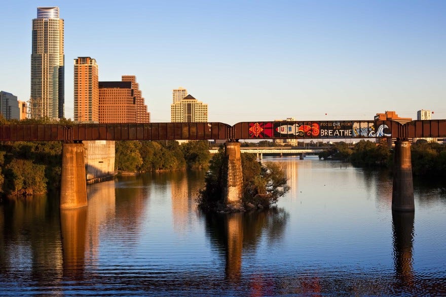 The train bridge over Lady Bird Lake, as seen in 2010. A mural that says "Focus One Point and Breathe" with a rocketship to the left and a stormcloud and a wave to the right.