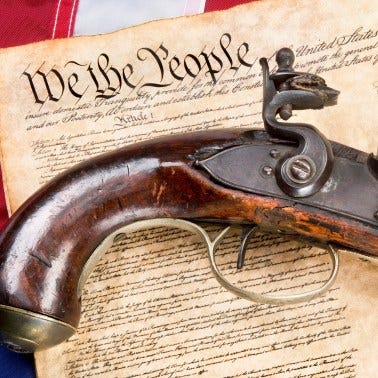 Flintlock pistol and We the People page of the Constitution